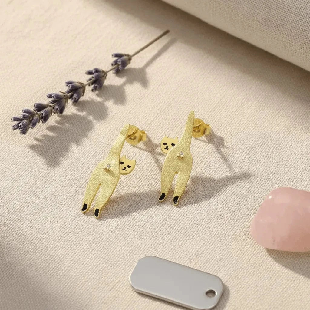 Pair of llama-shaped earrings on a beige surface with lavender flowers and a gray tag.