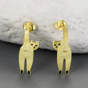 Gold cat-shaped earrings on a gray surface with a marble background