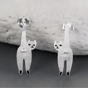 Silver cat-shaped earrings on a gray surface with a marble background