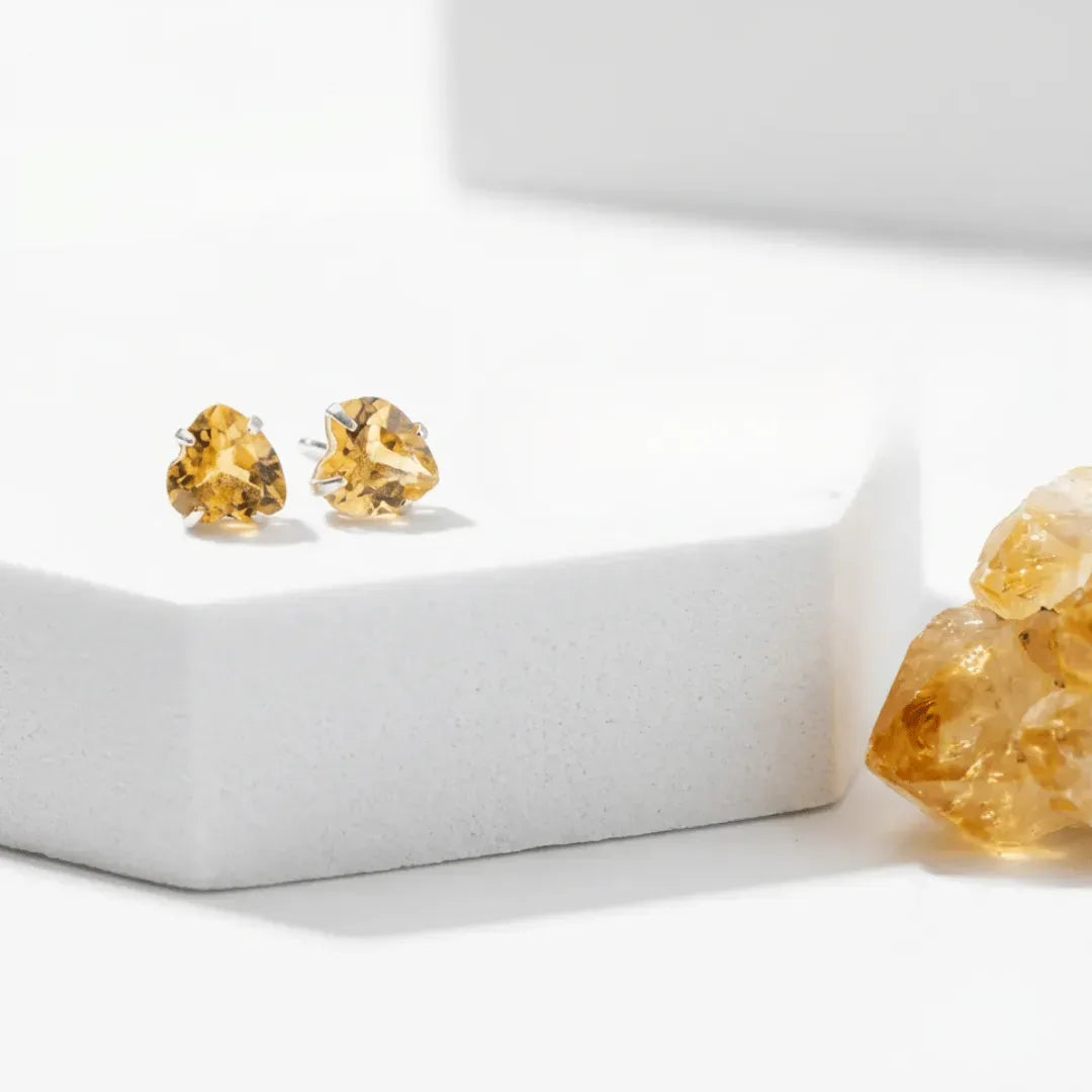 Gold stud earrings with a yellow gemstone on a white background