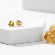 Gold stud earrings with a yellow gemstone on a white background