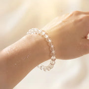 Close-up of a hand wearing a clear beaded bracelet against a blurred background