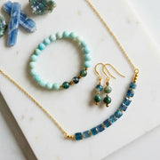 Faceted blue kyanite necklace with amazonite and moss agate stretch bracelet and matching moss agate drop earrings on white marble