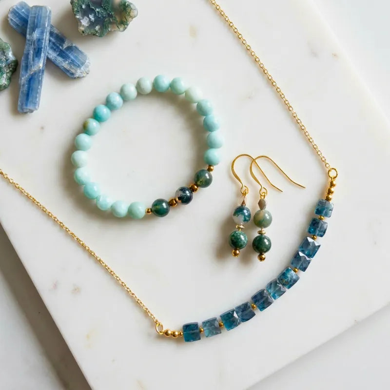 Faceted blue kyanite necklace with amazonite and moss agate stretch bracelet and matching moss agate drop earrings on white marble