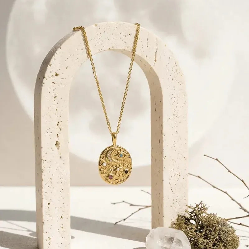 Gold necklace with a round pendant on a white stand with a natural background