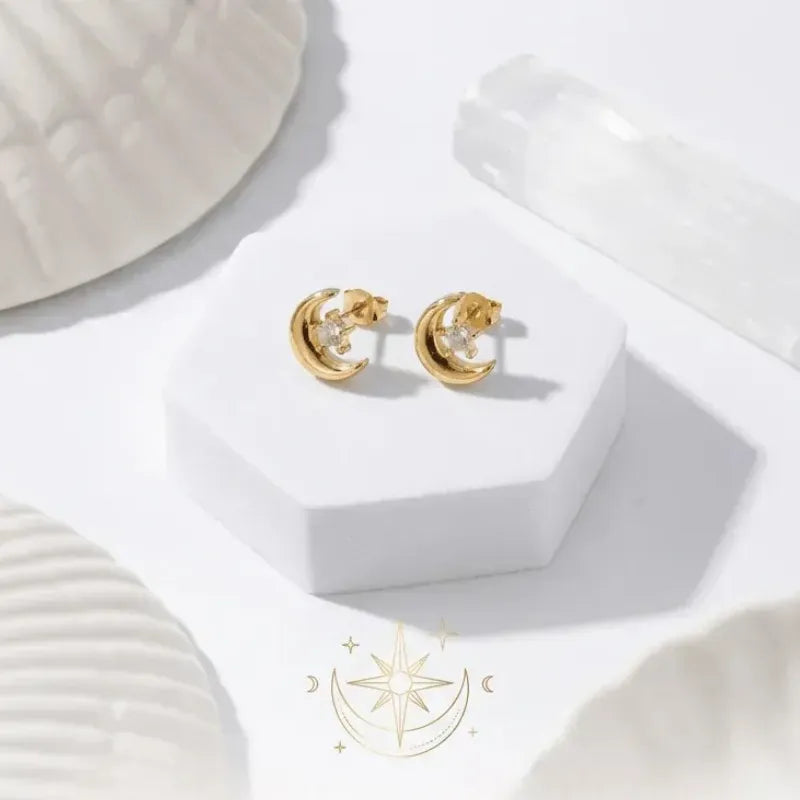 Gold hoop earrings on a white surface with a brand logo in the corner.