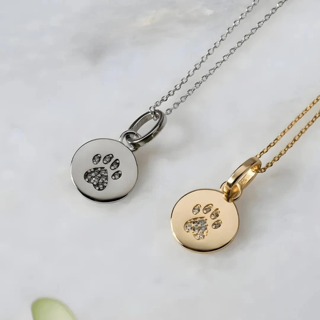 Two necklaces with paw print pendants on a light background