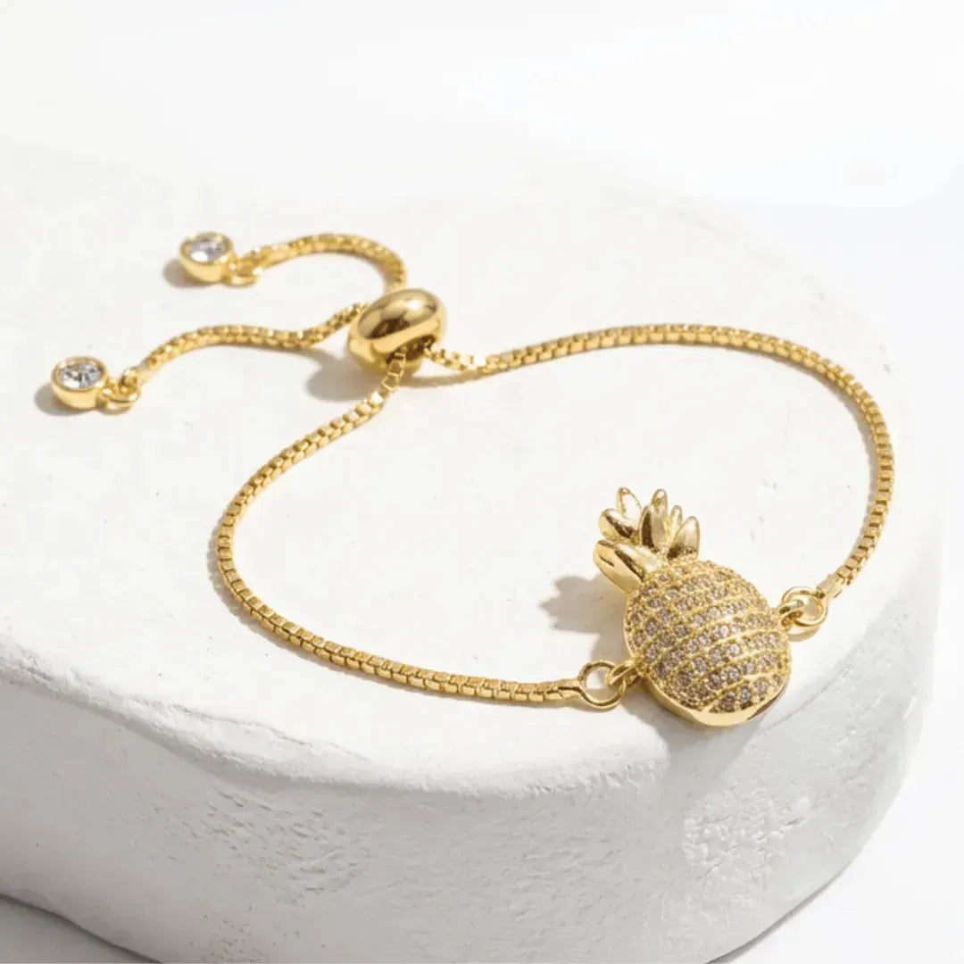 Gold bracelet with pineapple charm on a white background