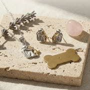 Jewelry set including a necklace, earrings, and a pendant on a textured surface with lavender and a pink stone.