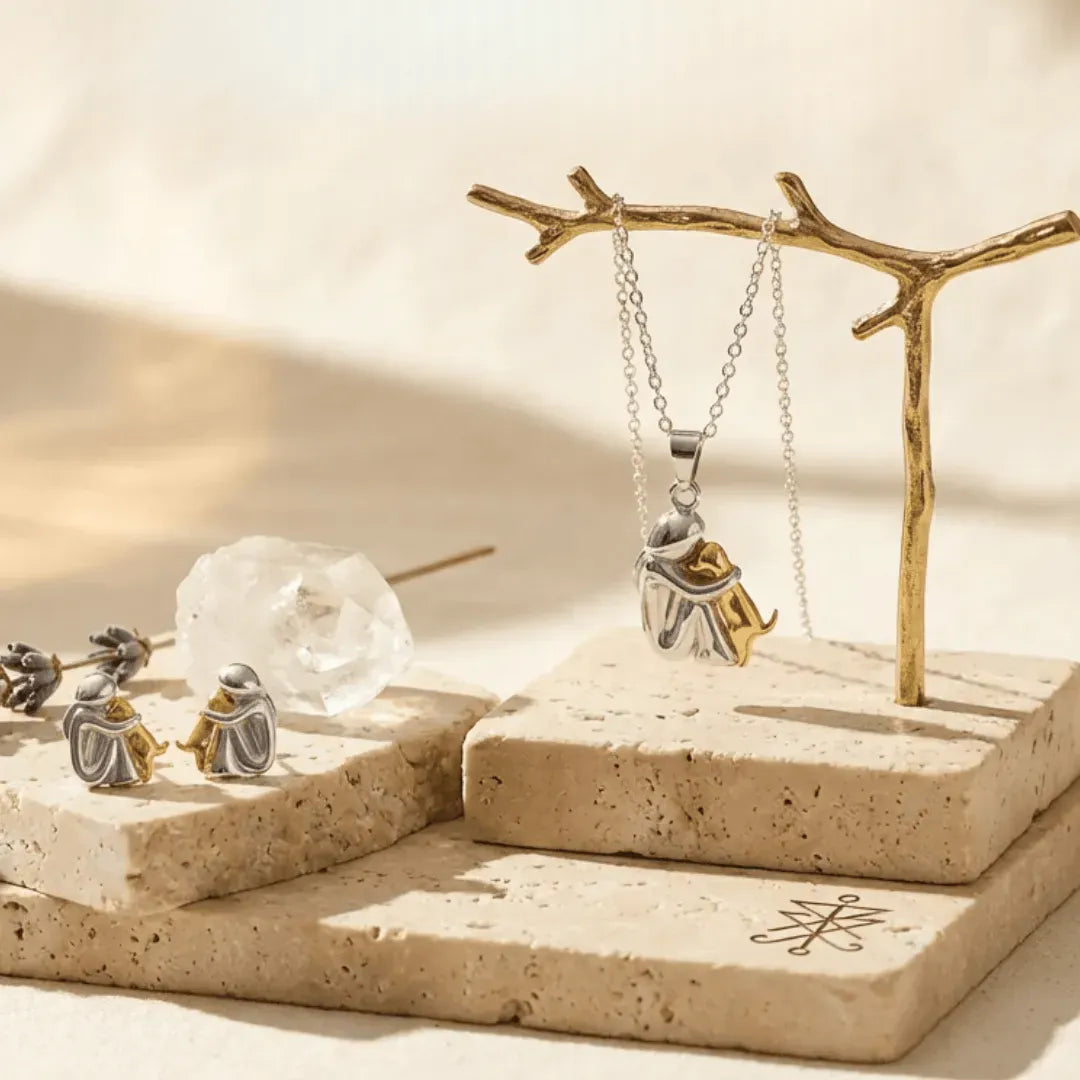 Silver jewelry set including a necklace and earrings on a natural stone surface with a branch stand.