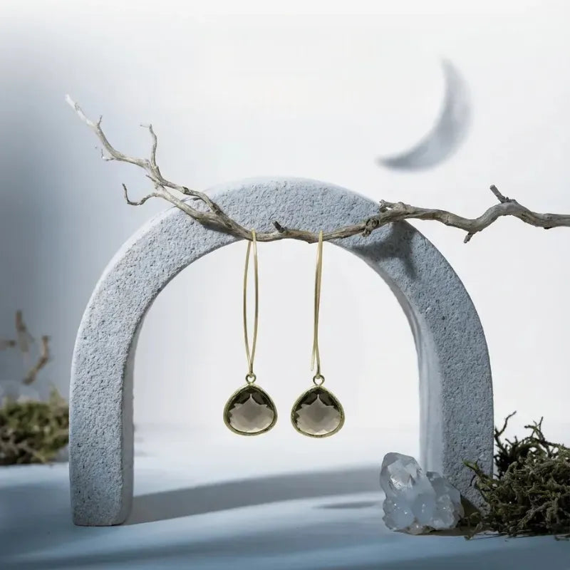 A pair of gold-toned dangle earrings with oval clear stone pendants 