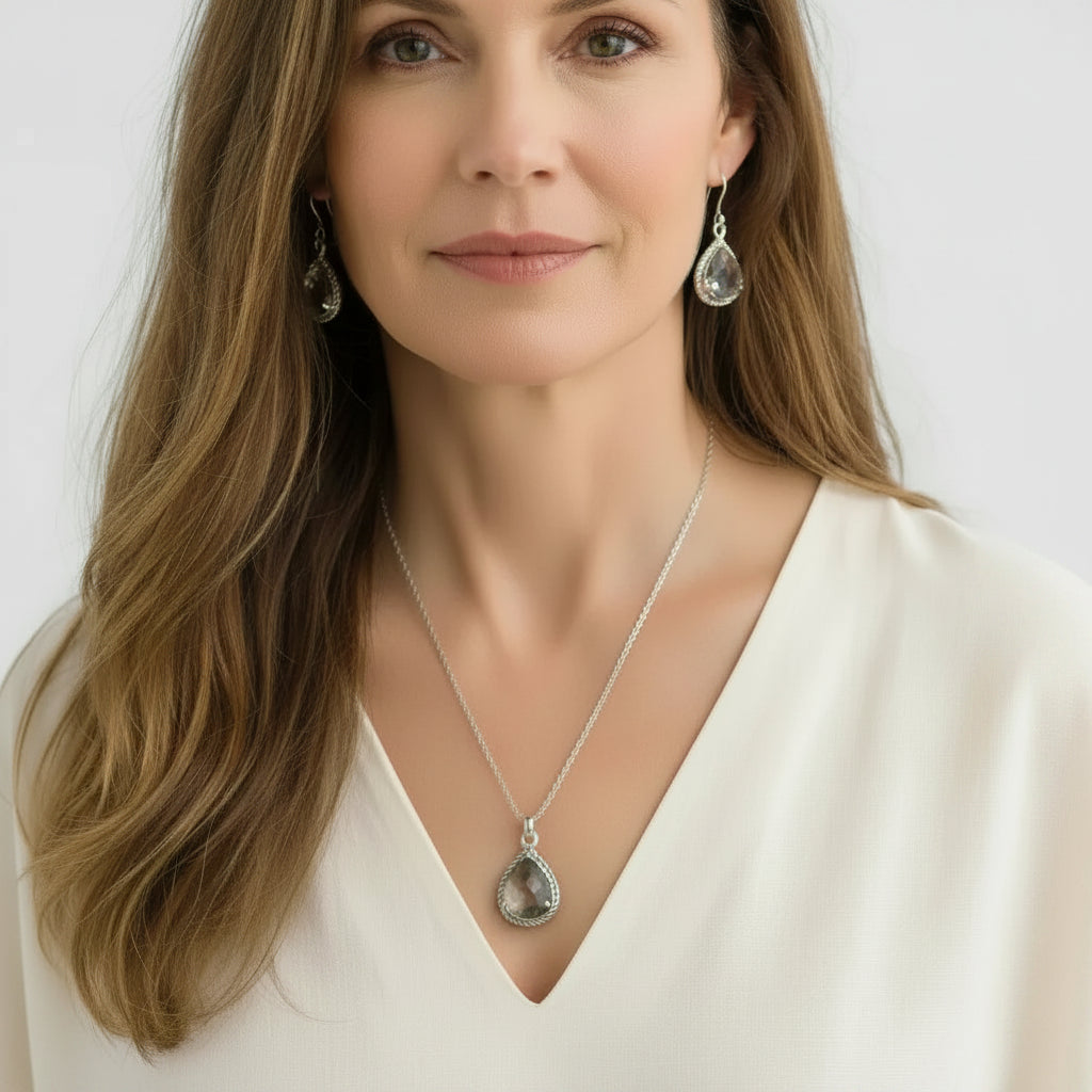 A woman wearing a silver teardrop pendant necklace and matching drop  