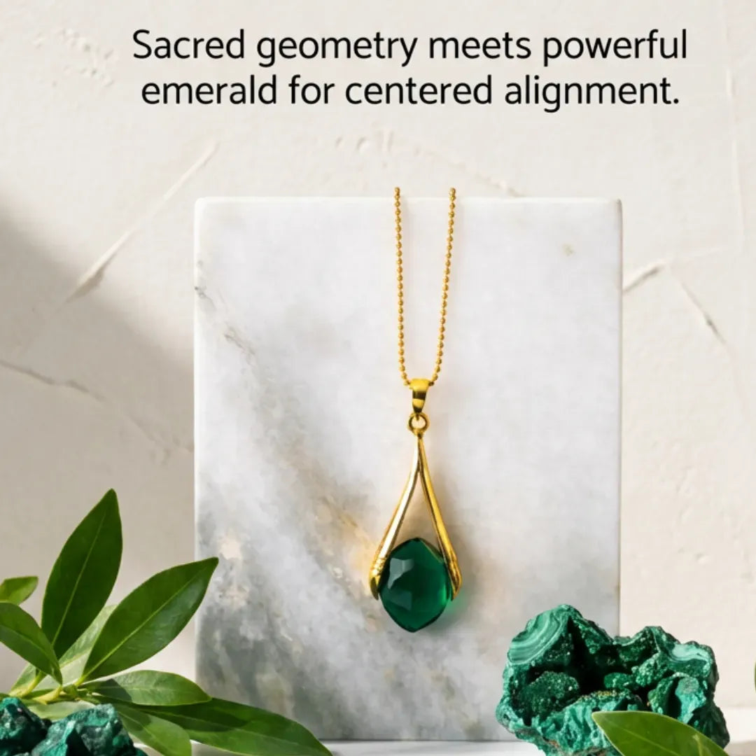 Gold necklace with a green pendant on a marble surface, surrounded by greenery.