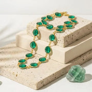 Green emerald necklace with gold accents on a textured stone surface