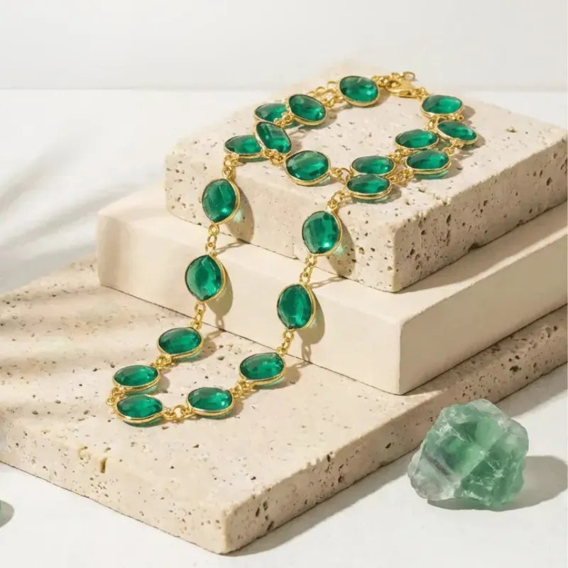 Green emerald necklace with gold accents on a textured stone surface