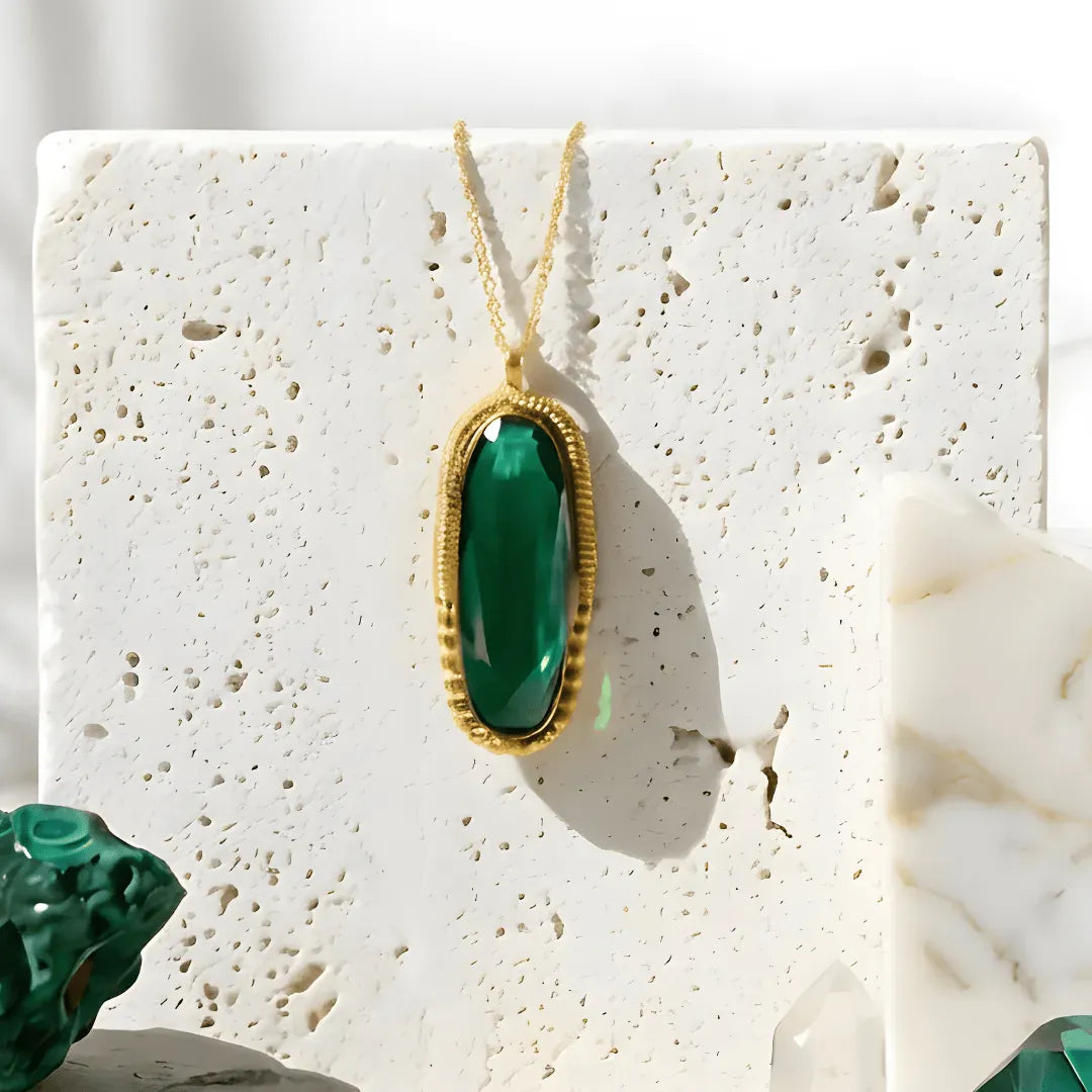 Green pendant necklace on a textured white surface with a blurred background