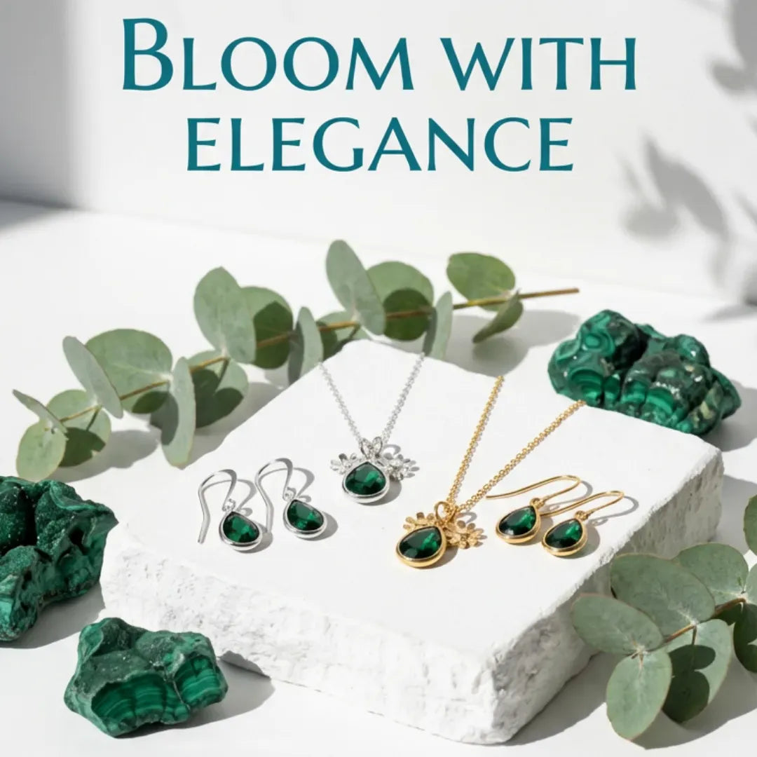 Jewelry set with green gemstones on a white stone surface with eucalyptus leaves, text 'Bloom with Elegance'.