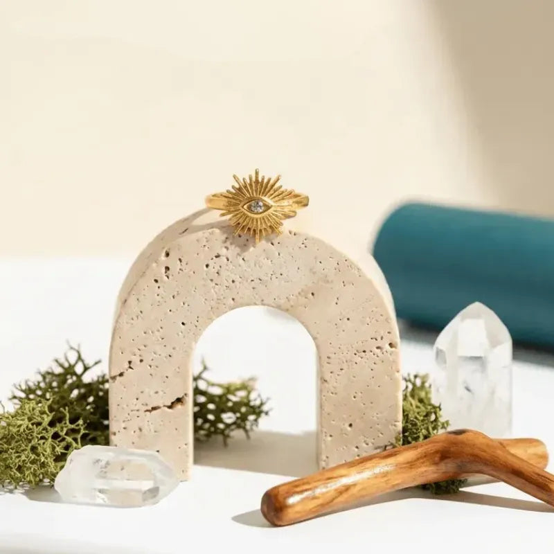 Decorative arch with crystals and a wooden stick on a neutral background