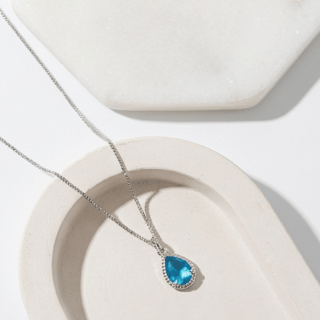 Necklace with a blue teardrop pendant on a white surface