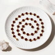 Garnet necklace with gold chain on a white plate
