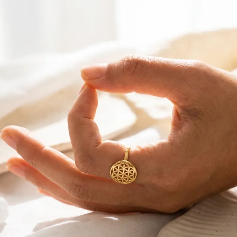 Hand wearing a gold ring with a geometric design on a blurred background