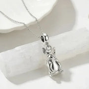 Silver cat pendant necklace on a white stone surface