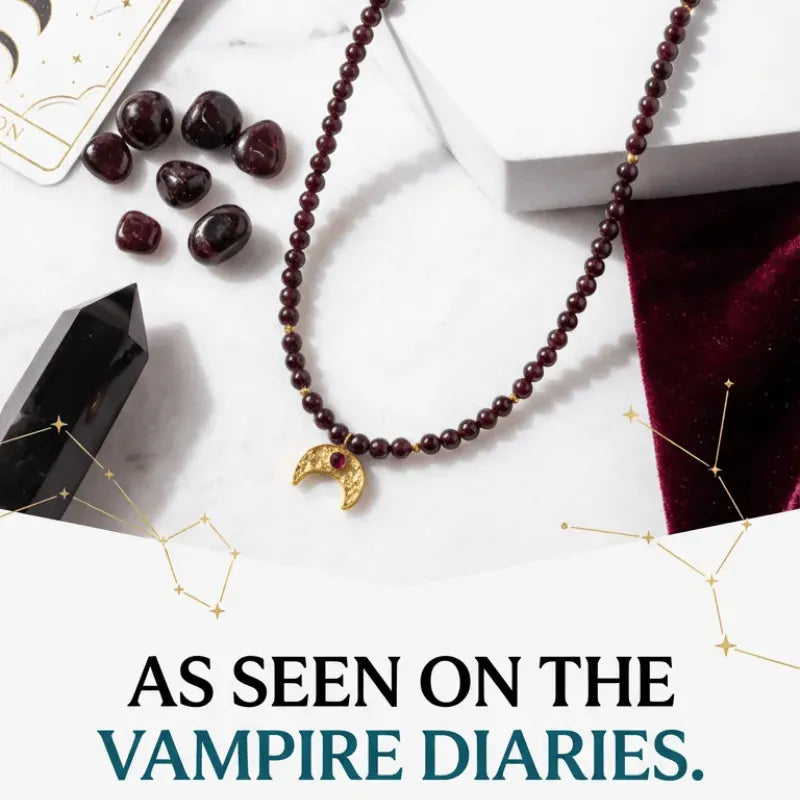 Necklace with maroon beads and gold crescent moon charm on a white surface with text 'As seen on The Vampire Diaries'.