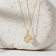 gold necklace hanging against a white stone with white background