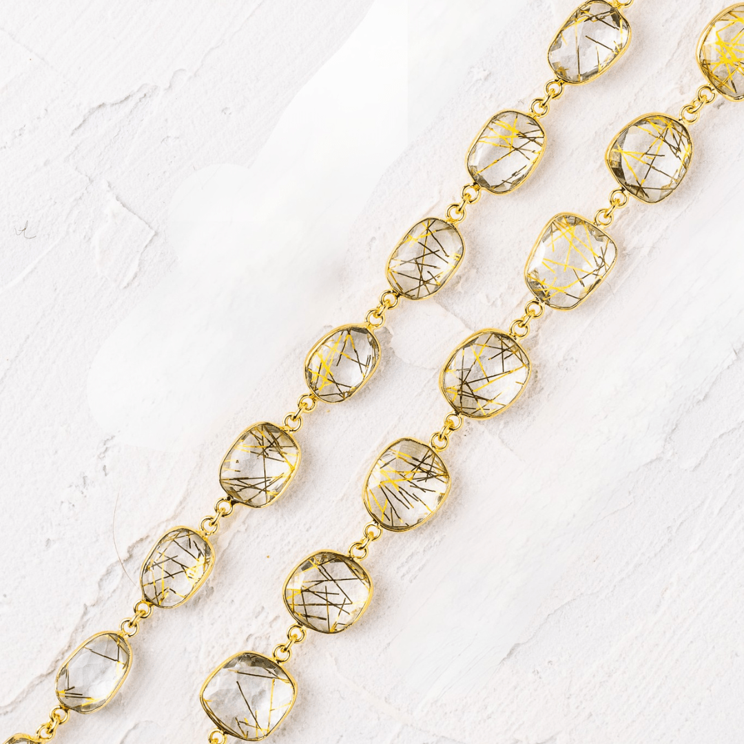 Gold necklace with clear gemstones on a textured white surface
