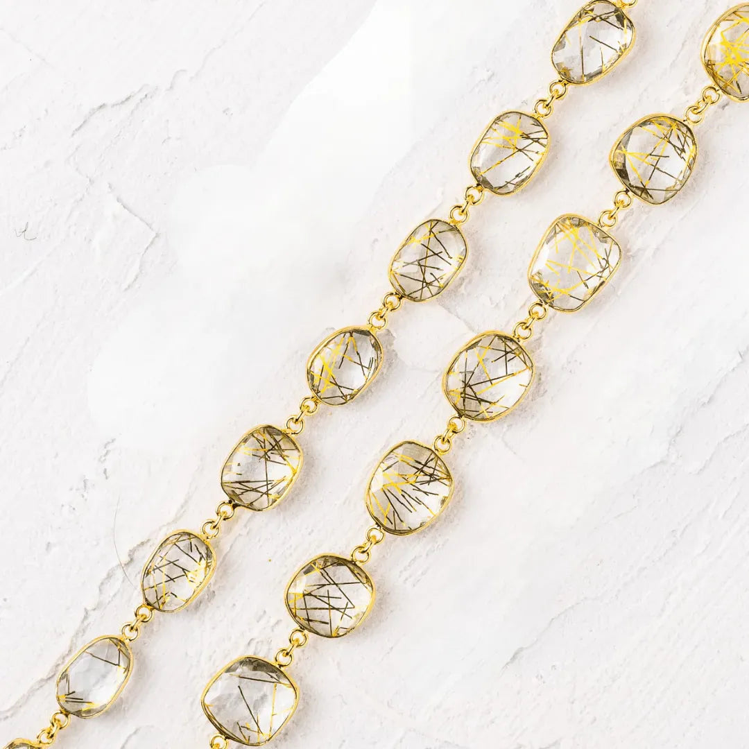 Gold necklace with clear gemstones on a textured white surface