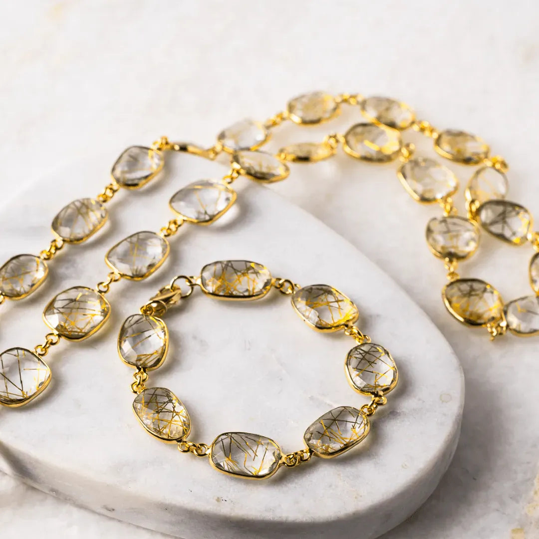 Gold necklace with clear gemstones on a marble surface