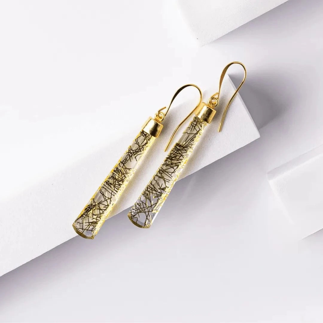 Gold earrings with intricate design on a light gray background