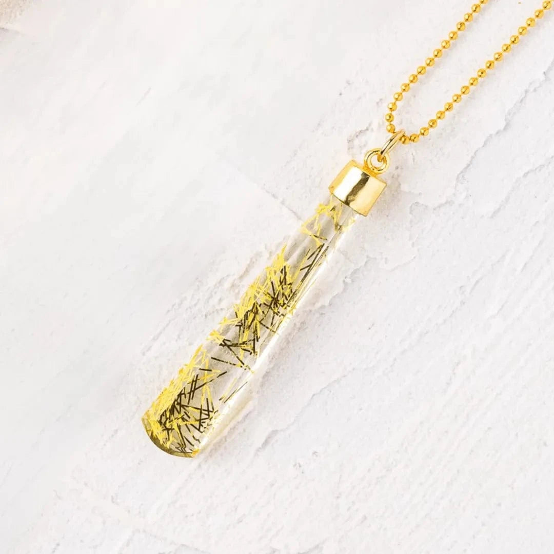 Necklace with a clear pendant containing yellow stones on a white background