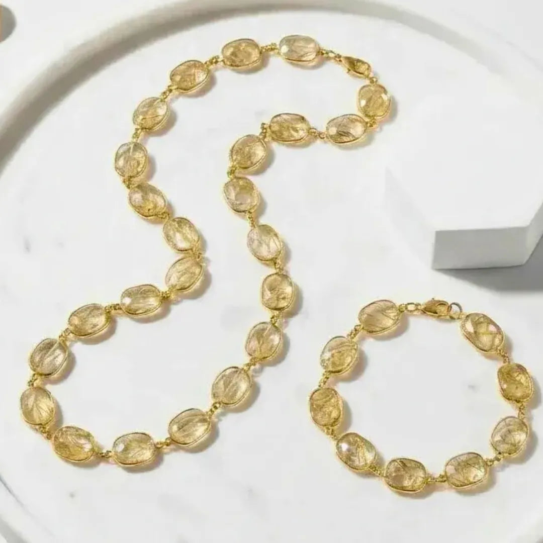 Gold necklace and bracelet set on a marble surface