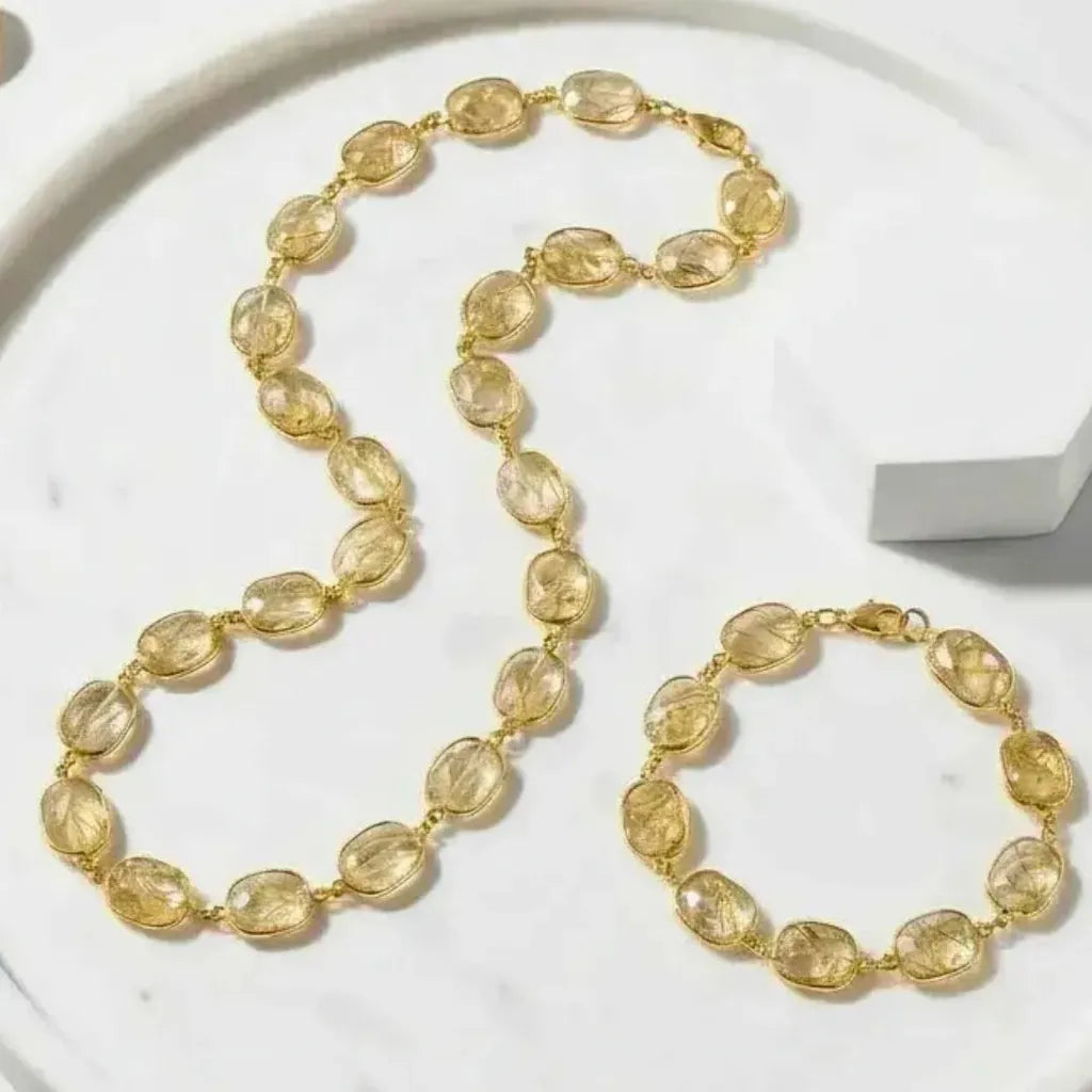 Gold necklace and bracelet set on a marble surface