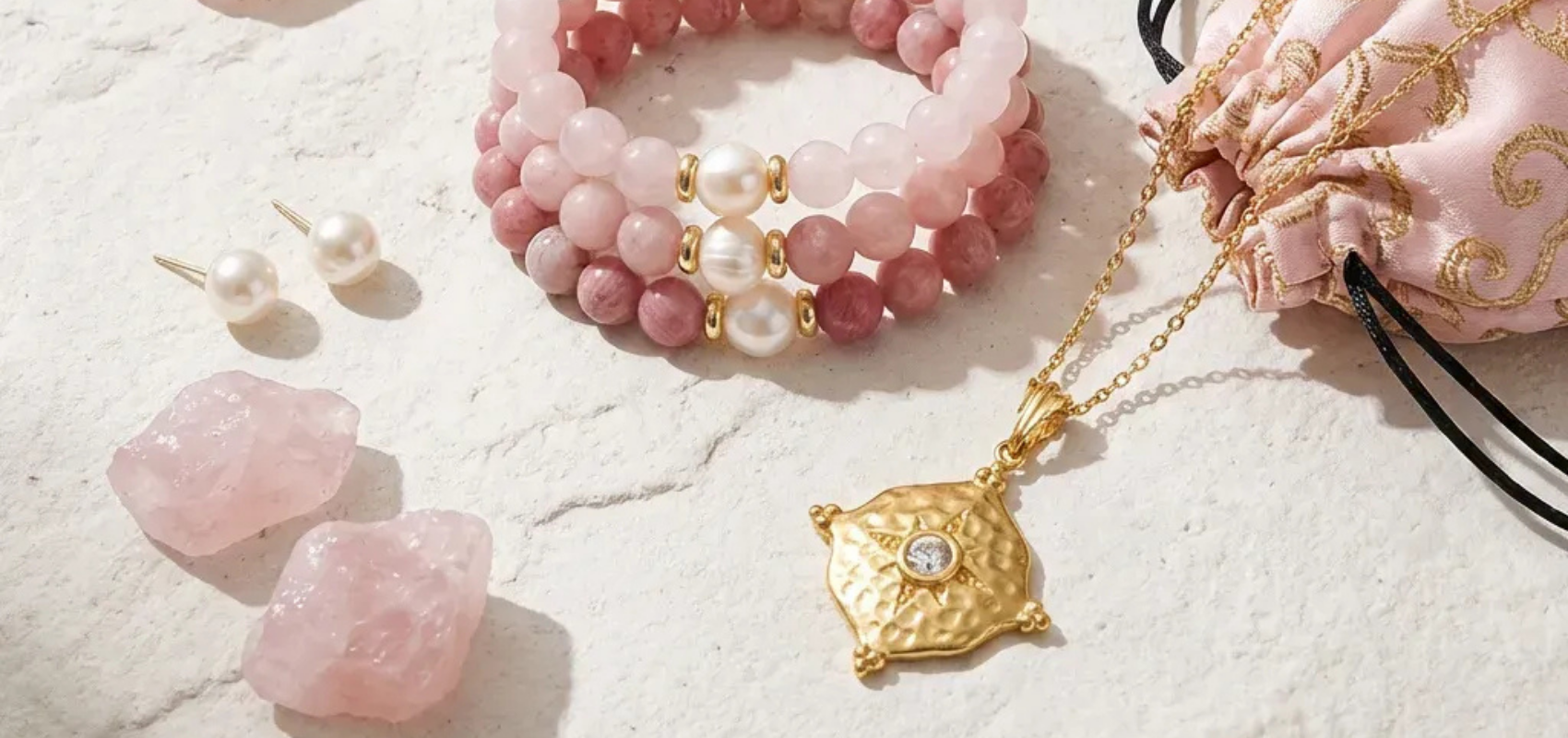 Jewelry set with pink beads, gold necklace, and earrings on a textured surface