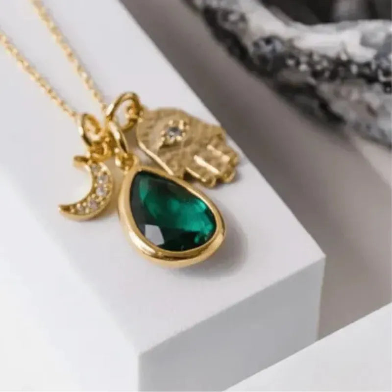 Gold plated hamsa hand necklace with crescent moon and emerald green glass teardrop