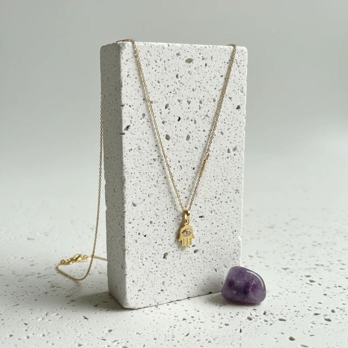 Gold hamsa hand necklace on a Mystic Soul gift card with amethyst