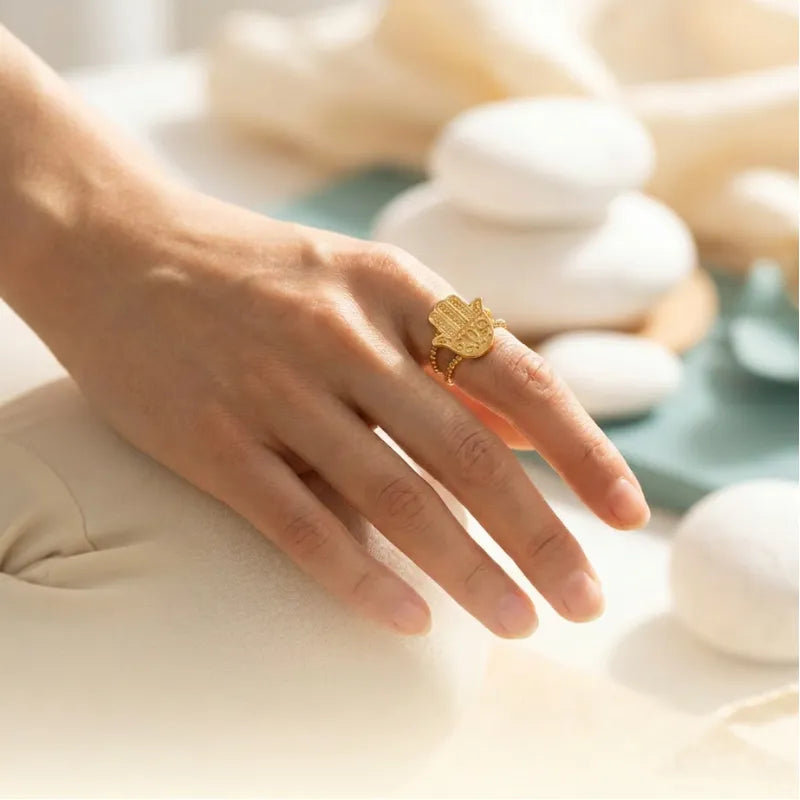 Hand wearing a gold ring with a blurred natural background