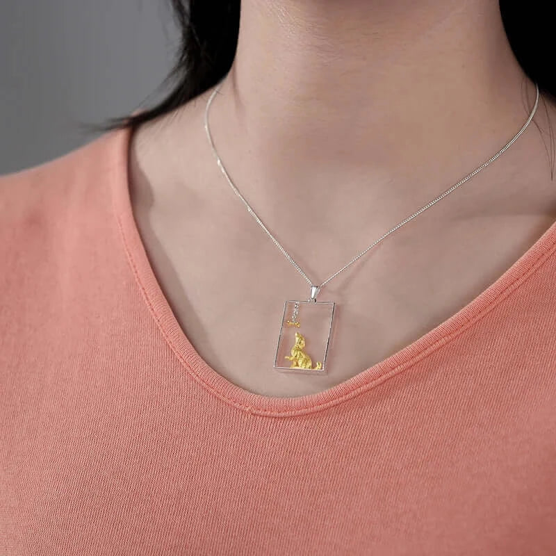 Transparent dog portrait pendant on silver chain worn by a person in an orange top, showcasing luxury pet jewelry.