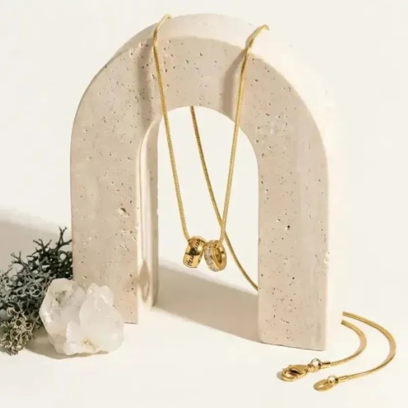 Gold necklace and bracelet on a beige arch with a white background
