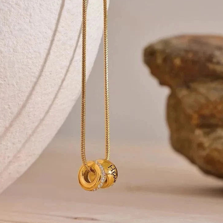 Gold necklace with a pendant on a textured surface