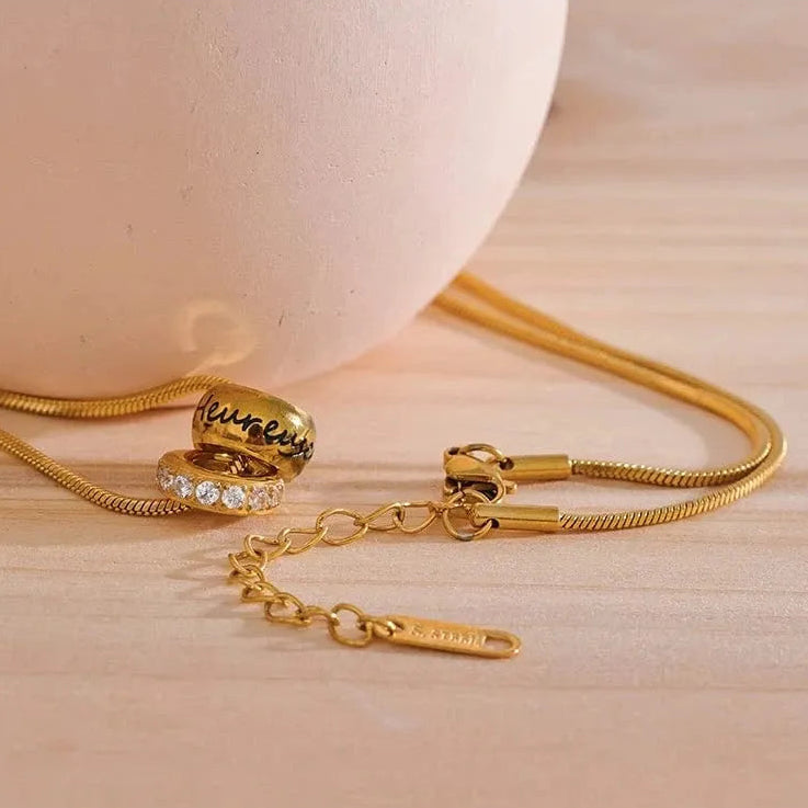 Gold necklace with a pendant on a light wooden surface