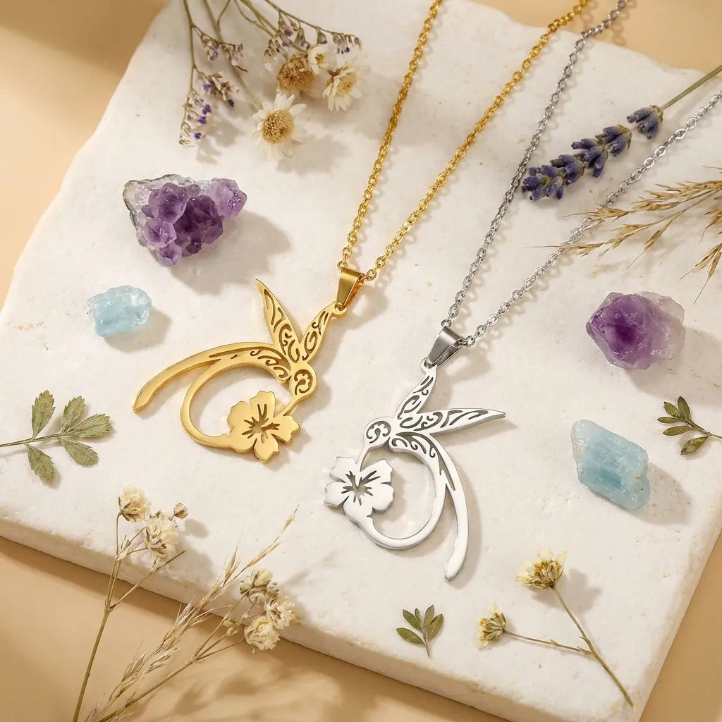 Two necklaces with floral pendants on a stone surface with crystals and flowers.