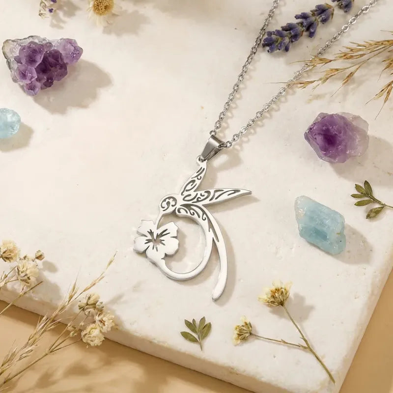Silver necklace with a floral pendant on a decorative surface with crystals and flowers