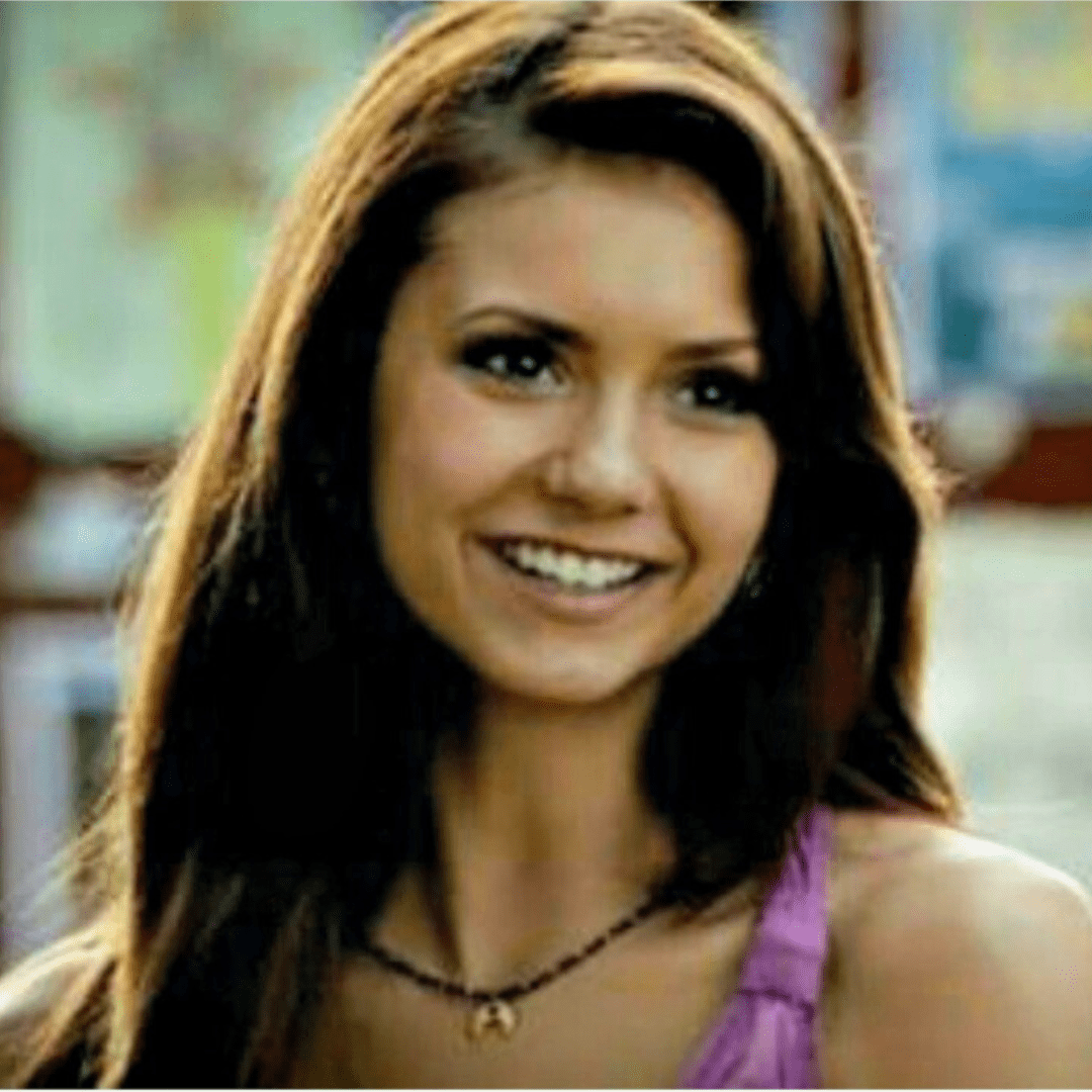 Woman with long brown hair wearing a purple top in an indoor setting