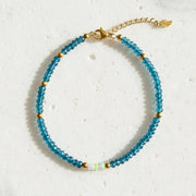A beaded bracelet with light blue faceted beads, small gold spacer beads, and moonstone