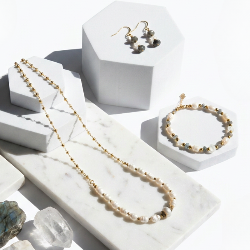 Jewelry set including necklace, earrings, and bracelet on a white marble surface.