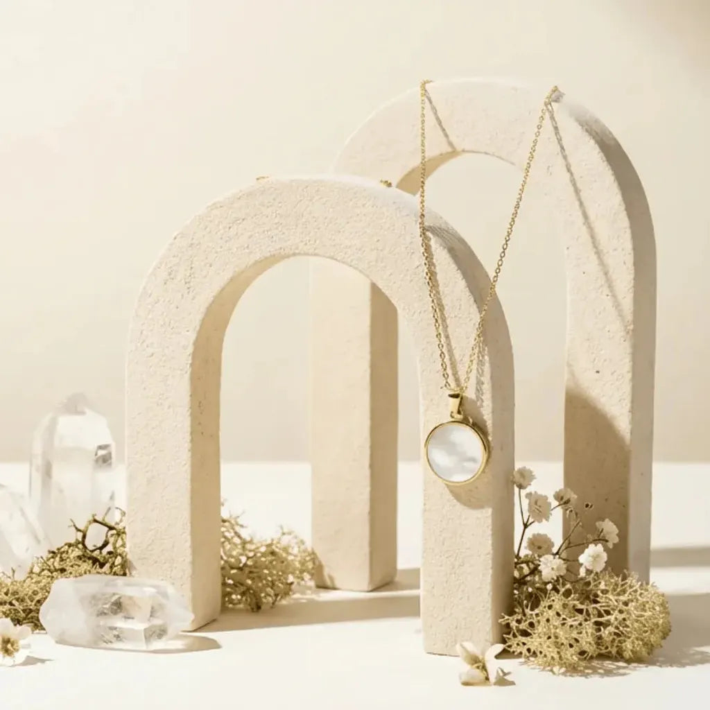 Necklace with a circular pendant hanging from a beige arch against a neutral background
