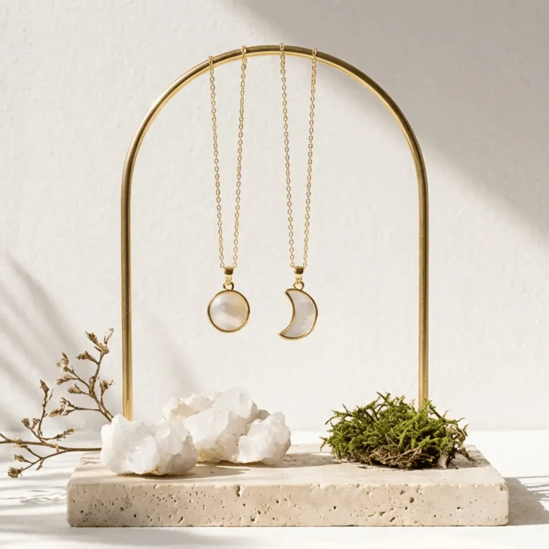 Gold necklaces on a decorative stand with white stones and greenery